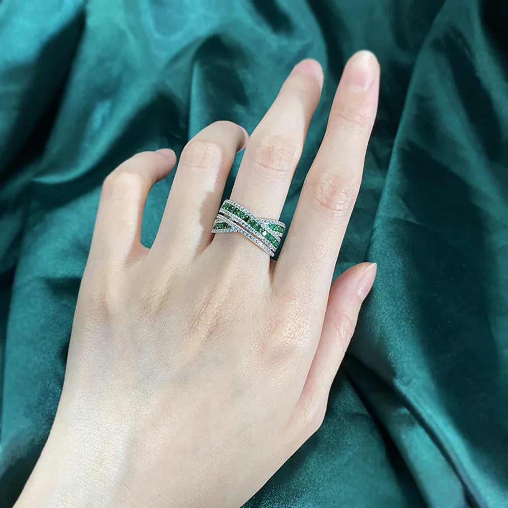 An exquisite X-shaped ring, crafted from 925 sterling silver and set with dazzling emerald gemstones. A timeless piece that reflects elegance and sophistication.