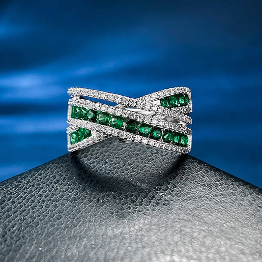 An exquisite X-shaped ring, crafted from 925 sterling silver and set with dazzling emerald gemstones. A timeless piece that reflects elegance and sophistication.